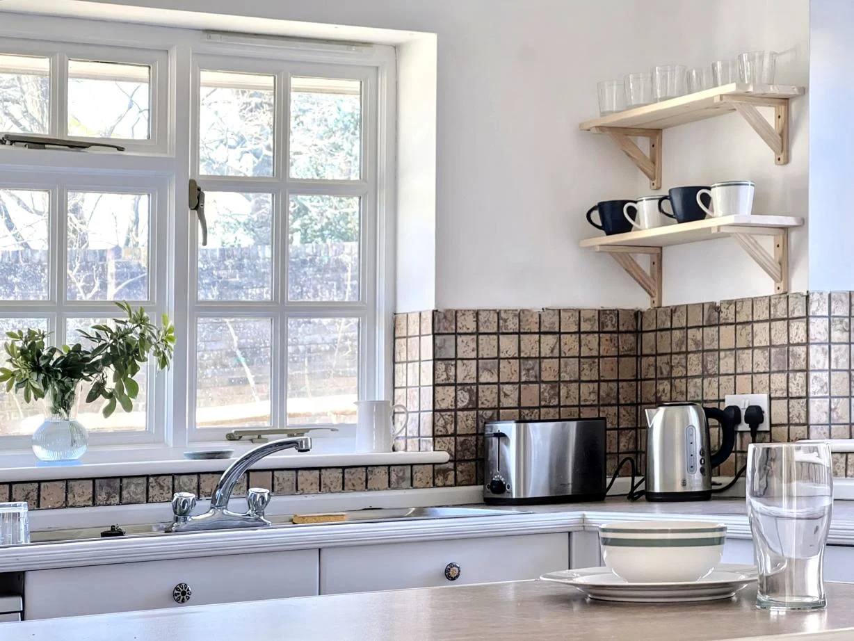 Kitchen window, sink and open shelving at Cocksfield House