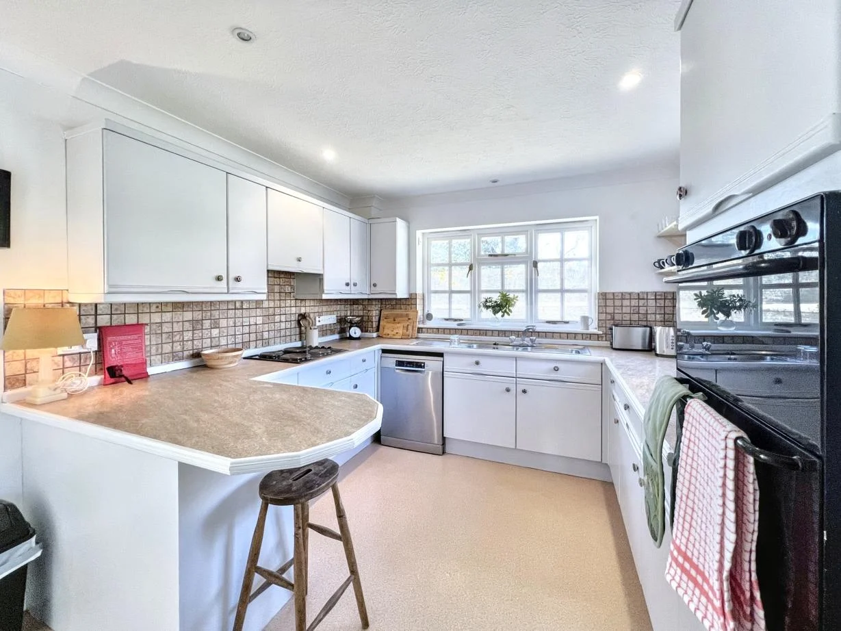 Bright kitchen with white cabinetry and tiled splashback at Cocksfield House